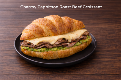 Charmy Pappitson Roast Beef Croissant on a black plate with a wooden background